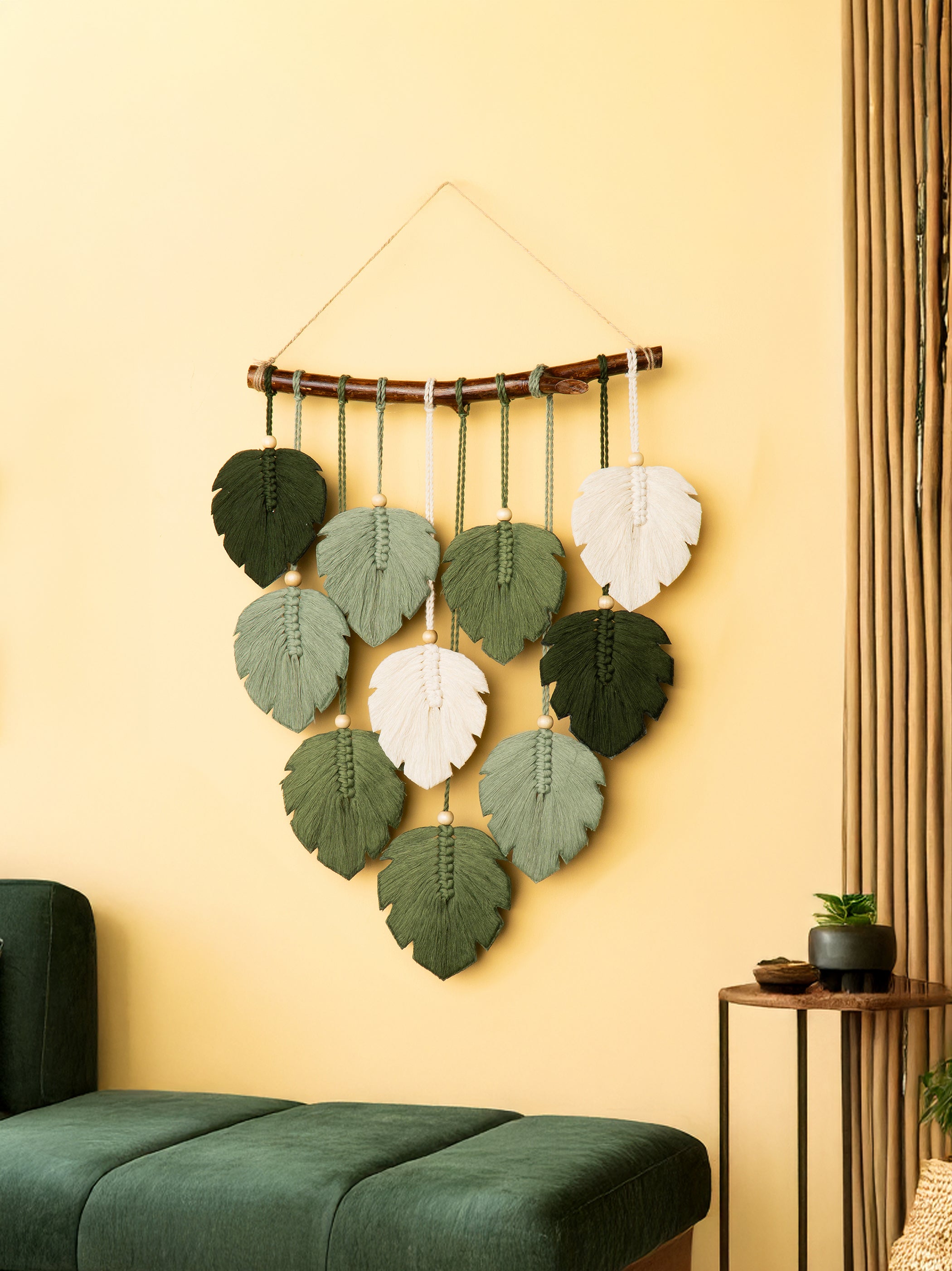 Decorative wall hanging with leaf-shaped leaves on a yellow wall.