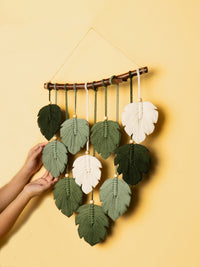 Handmade leaf-shaped wall hanging with green and white leaves on a yellow background