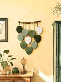Decorative wall hanging with leaf patterns on a yellow wall.