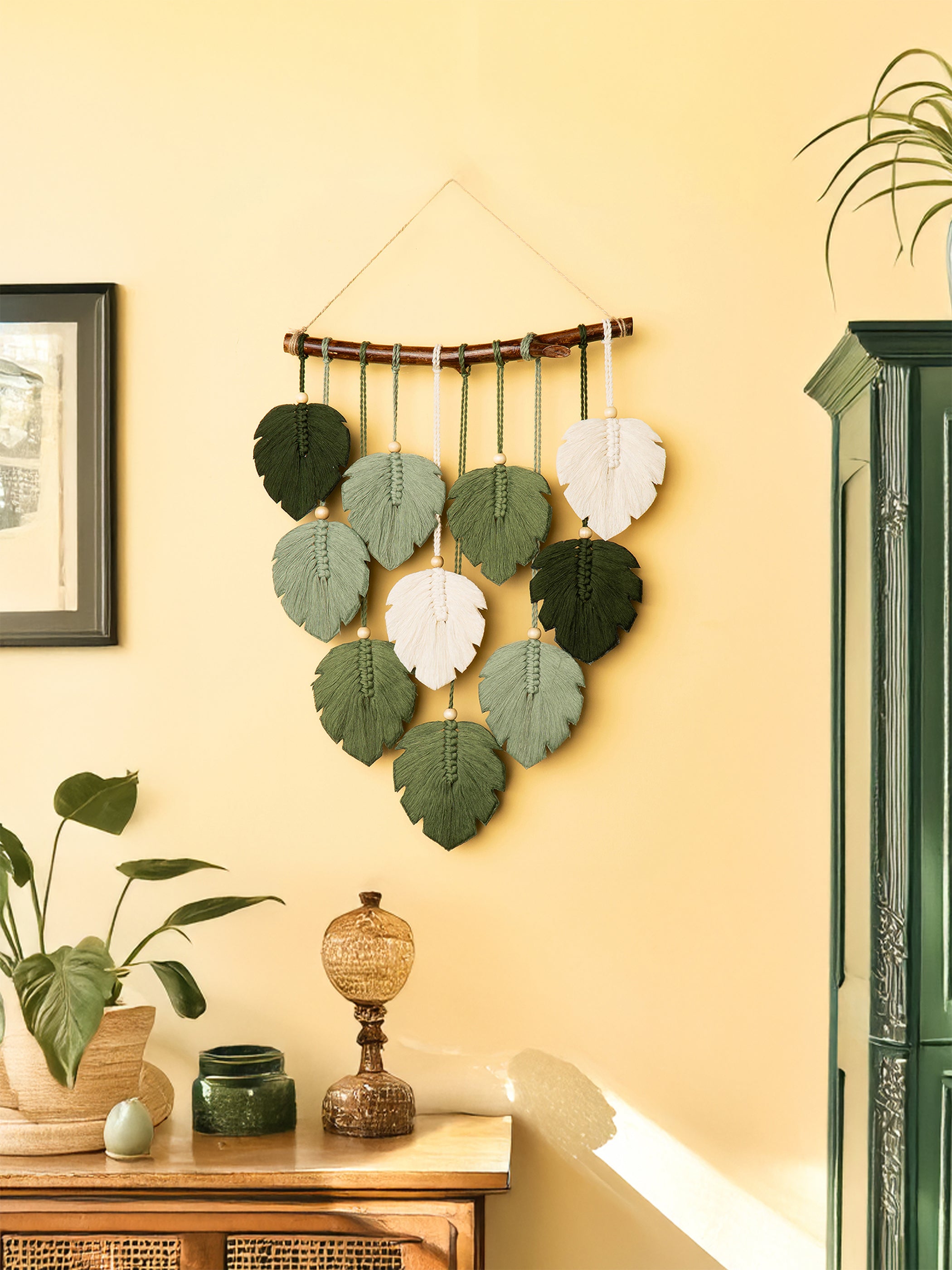 Decorative wall hanging with leaf patterns on a yellow wall.