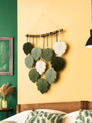 Decorative wall hanging with leaf patterns on a yellow wall.