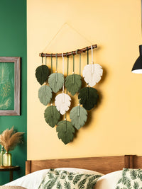 Decorative wall hanging with leaf patterns on a yellow wall.