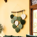 Decorative wall hanging with leaf-shaped elements on a yellow wall.