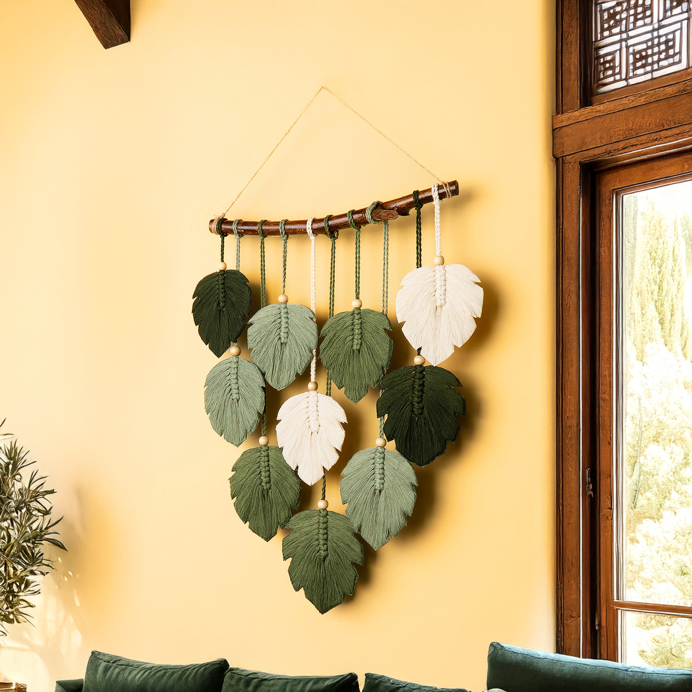 Decorative wall hanging with leaf-shaped elements on a yellow wall.
