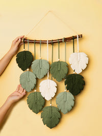 Handmade leaf-shaped wall hanging with green and white leaves on a yellow background