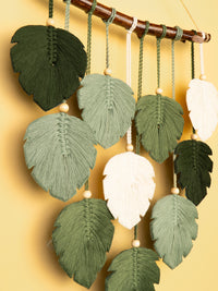 Decorative leaf-shaped ornaments hanging from a rod against a yellow background