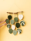 Handmade leaf-shaped wall hanging with green and white leaves on a yellow background