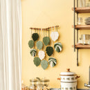 Decorative wall hanging with leaf-shaped elements on a yellow wall.