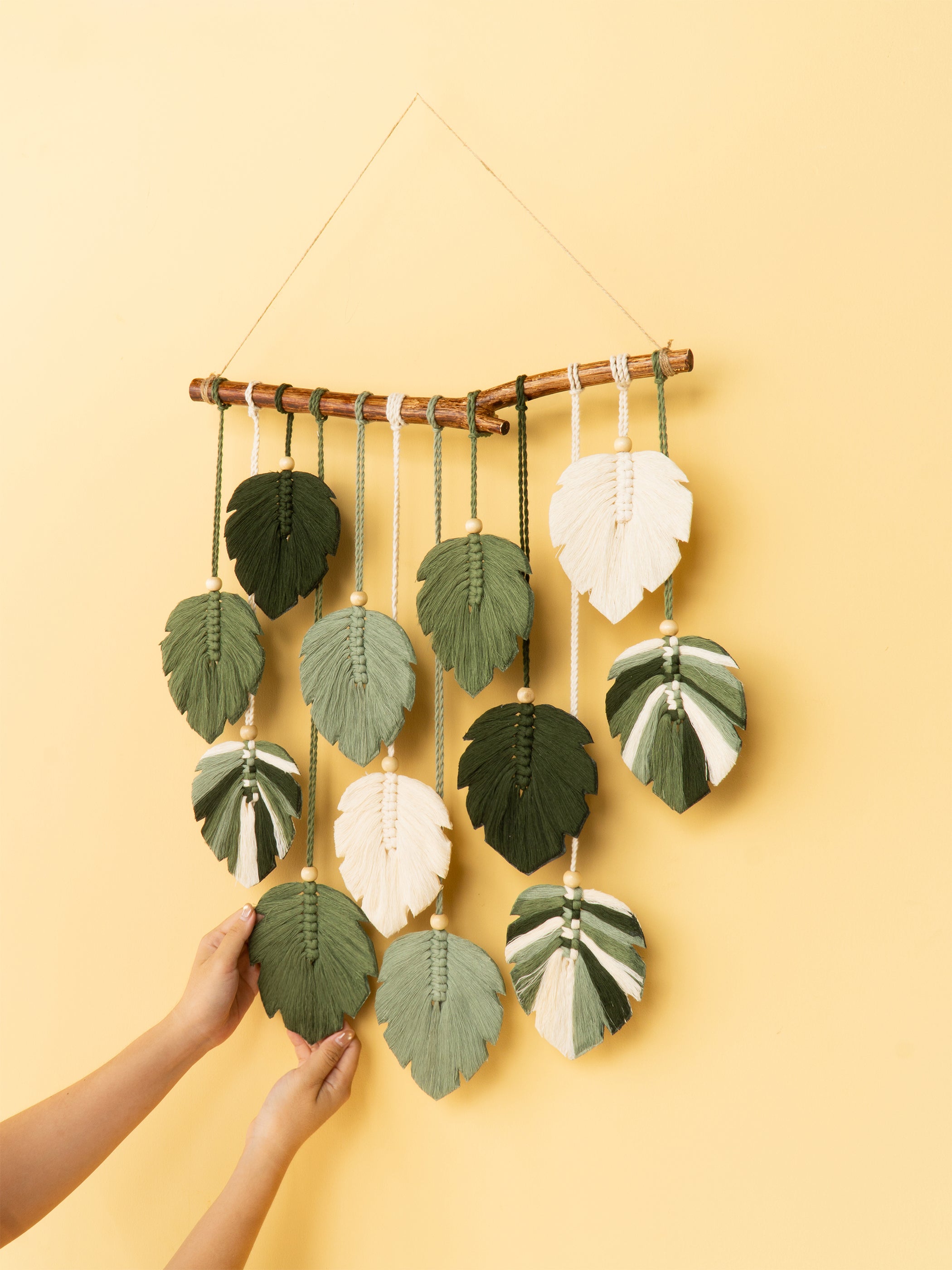 Wall hanging with leaf-shaped decorations on a yellow background