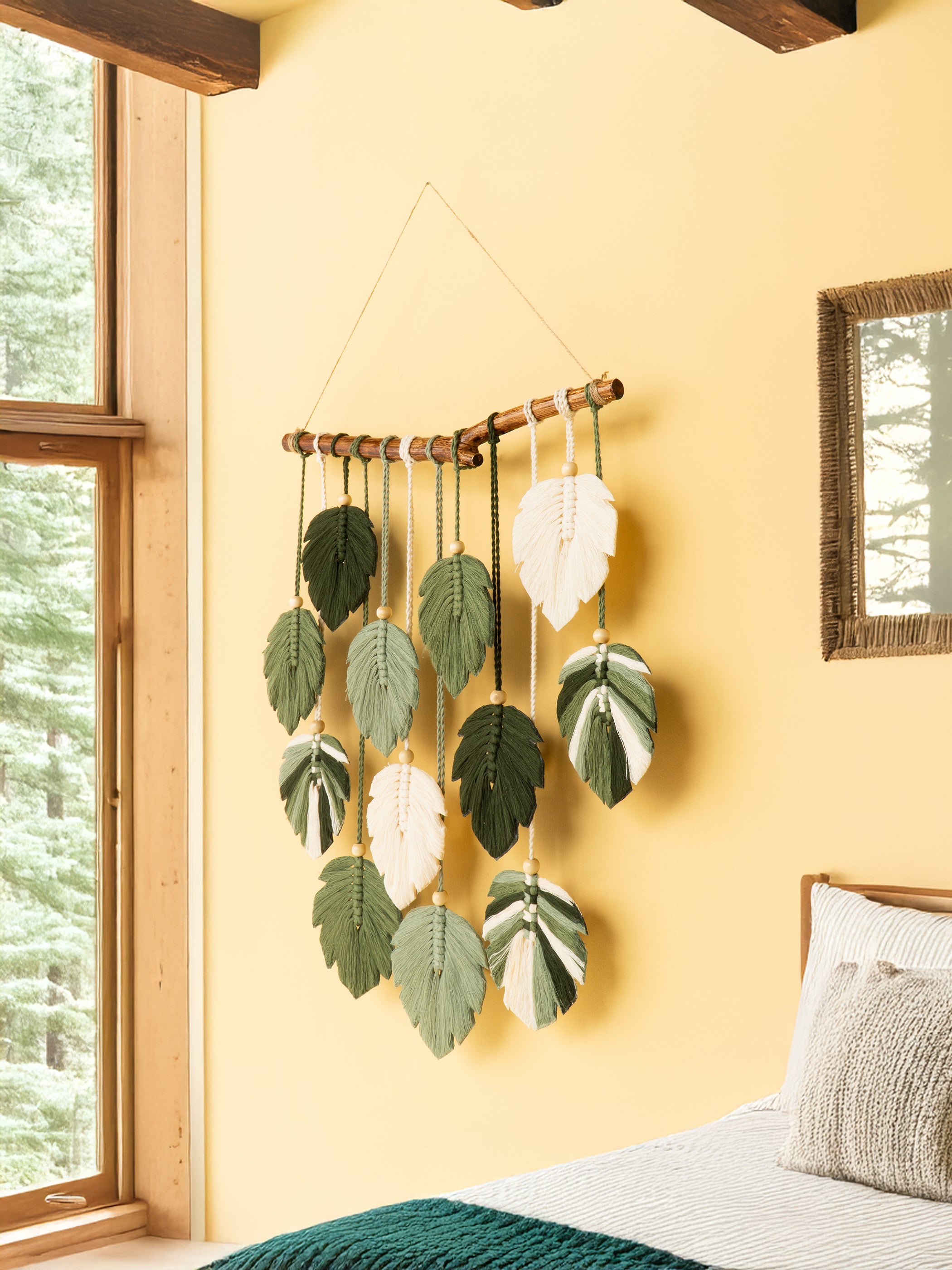 Decorative wall hanging with leaf patterns on a yellow wall next to a window.