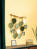 Decorative wall hanging with leaf-shaped leaves on a yellow wall.