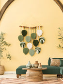 Decorative wall hanging with leaf patterns on a yellow wall.