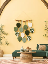 Decorative wall hanging with leaf patterns on a yellow wall.