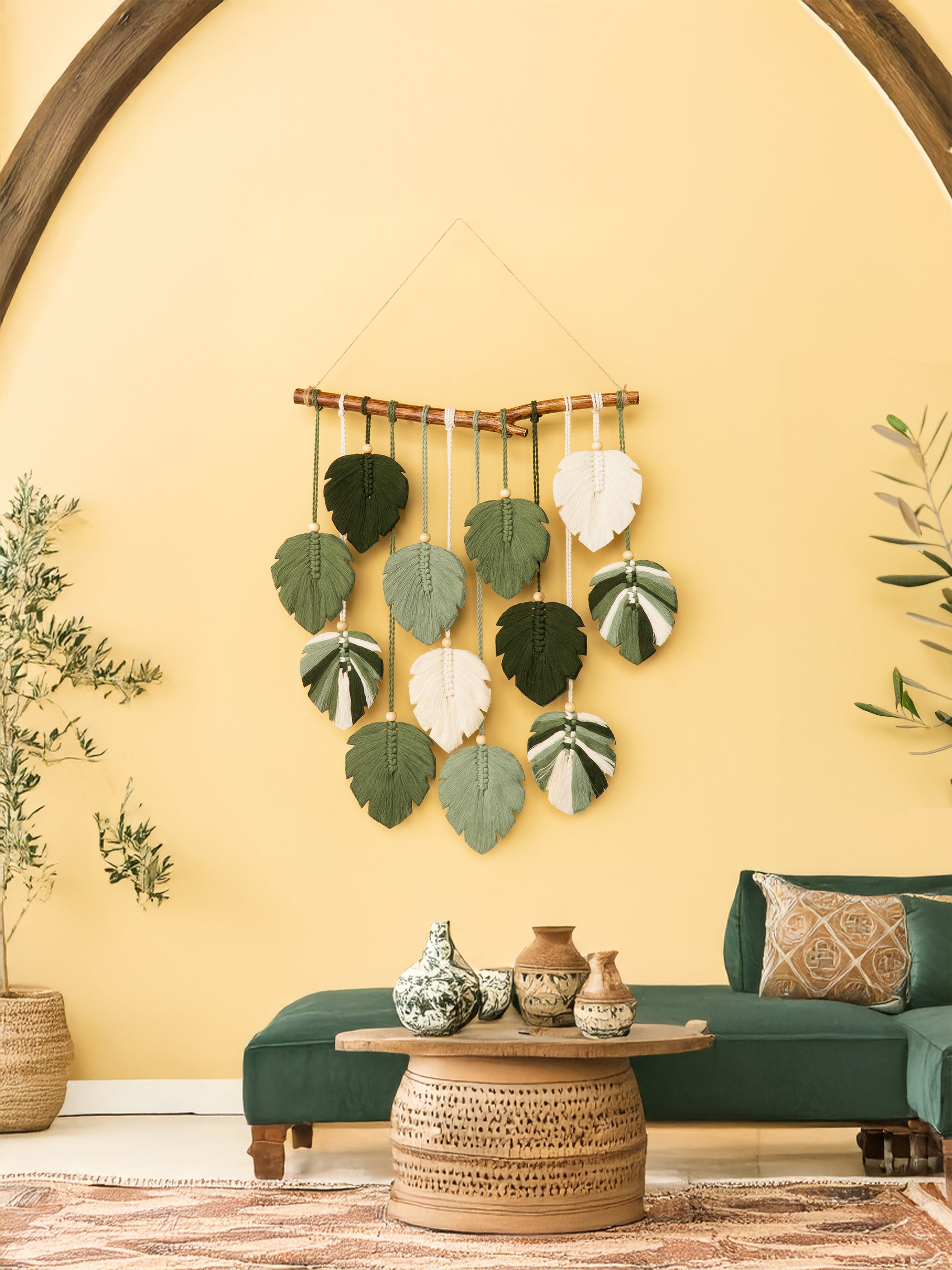 Decorative wall hanging with leaf patterns on a yellow wall.