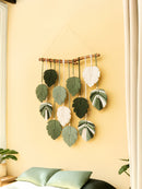 Decorative wall hanging with leaf-shaped ornaments on a yellow wall.