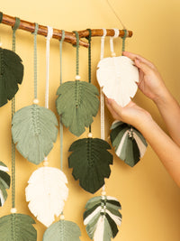 Decorative wall hanging with leaf-shaped ornaments on a yellow background
