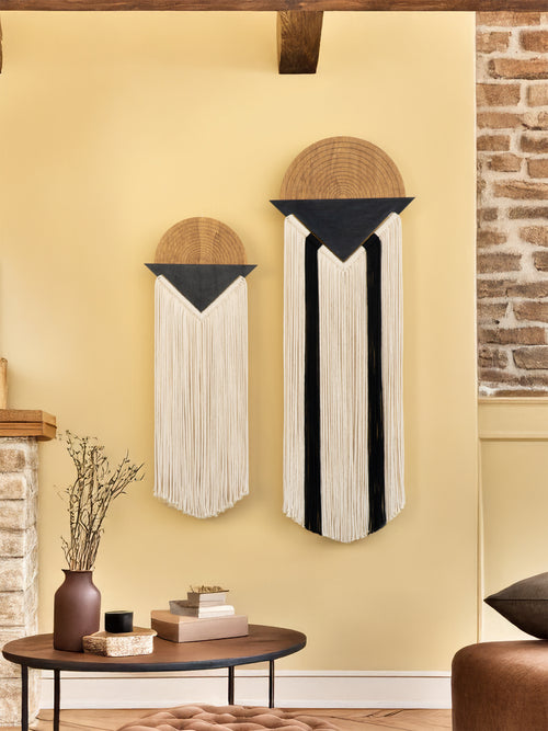 Decorative wall hangings on a yellow wall with a brick fireplace.