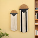 Two wall hangings with geometric designs on a yellow wall next to a bookshelf.