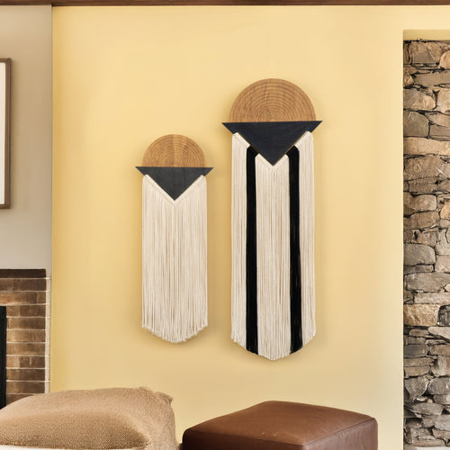 Two decorative wall hangings on a yellow wall with a stone fireplace.
