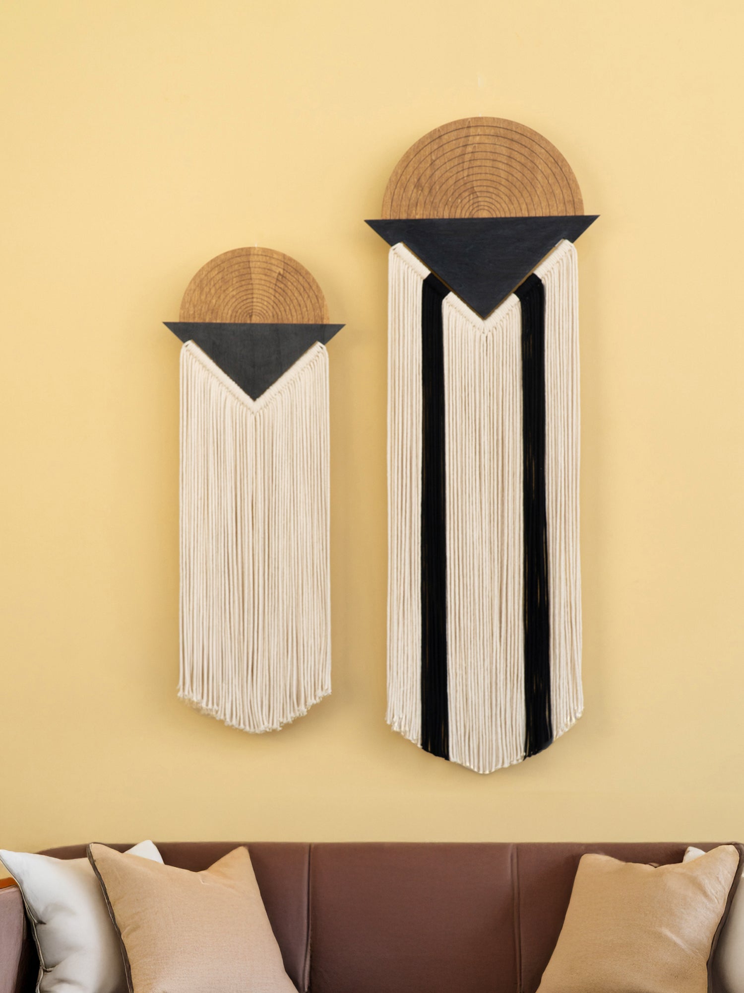 Two wall art pieces with geometric designs on a yellow wall.