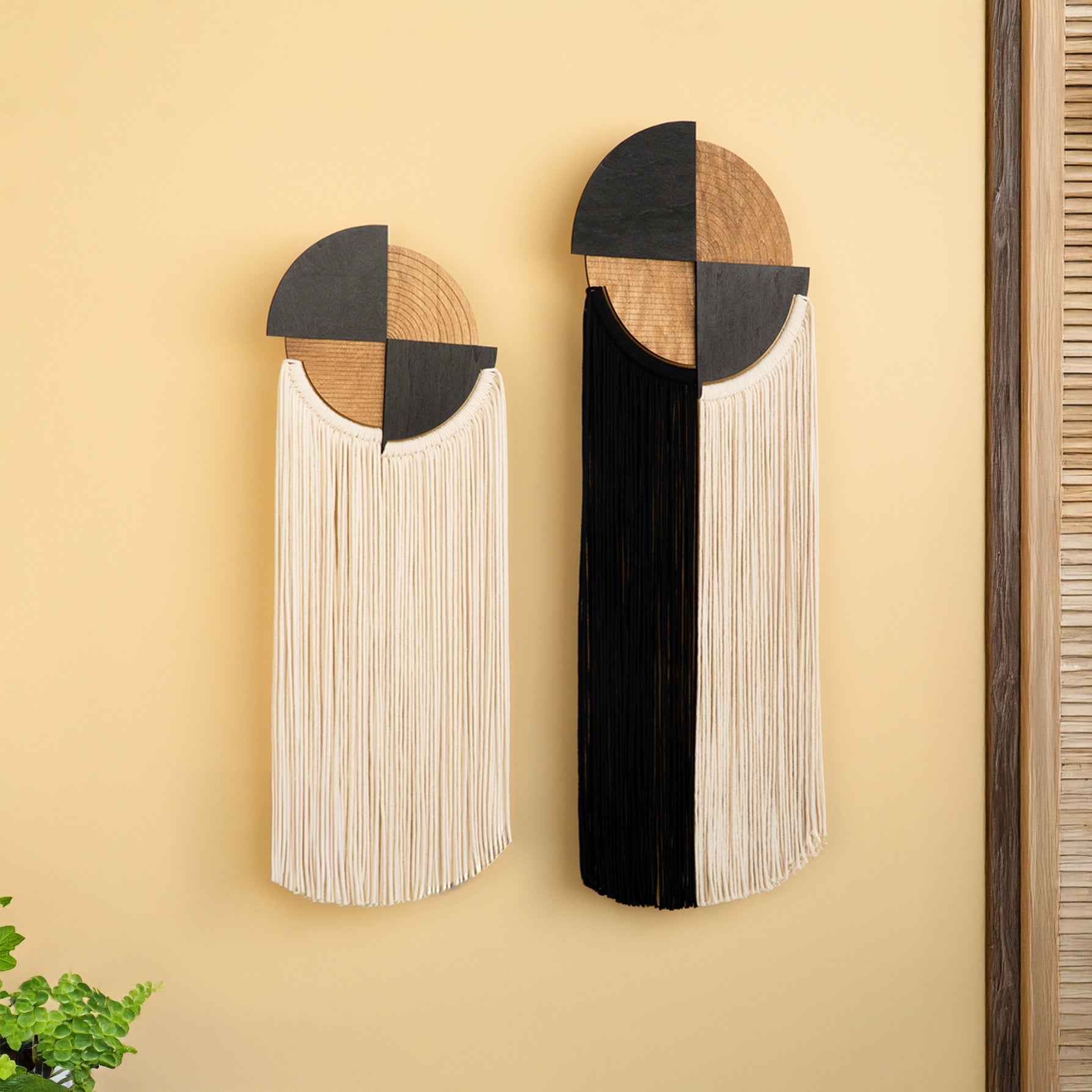 Two decorative wall art pieces with geometric designs on a beige wall.