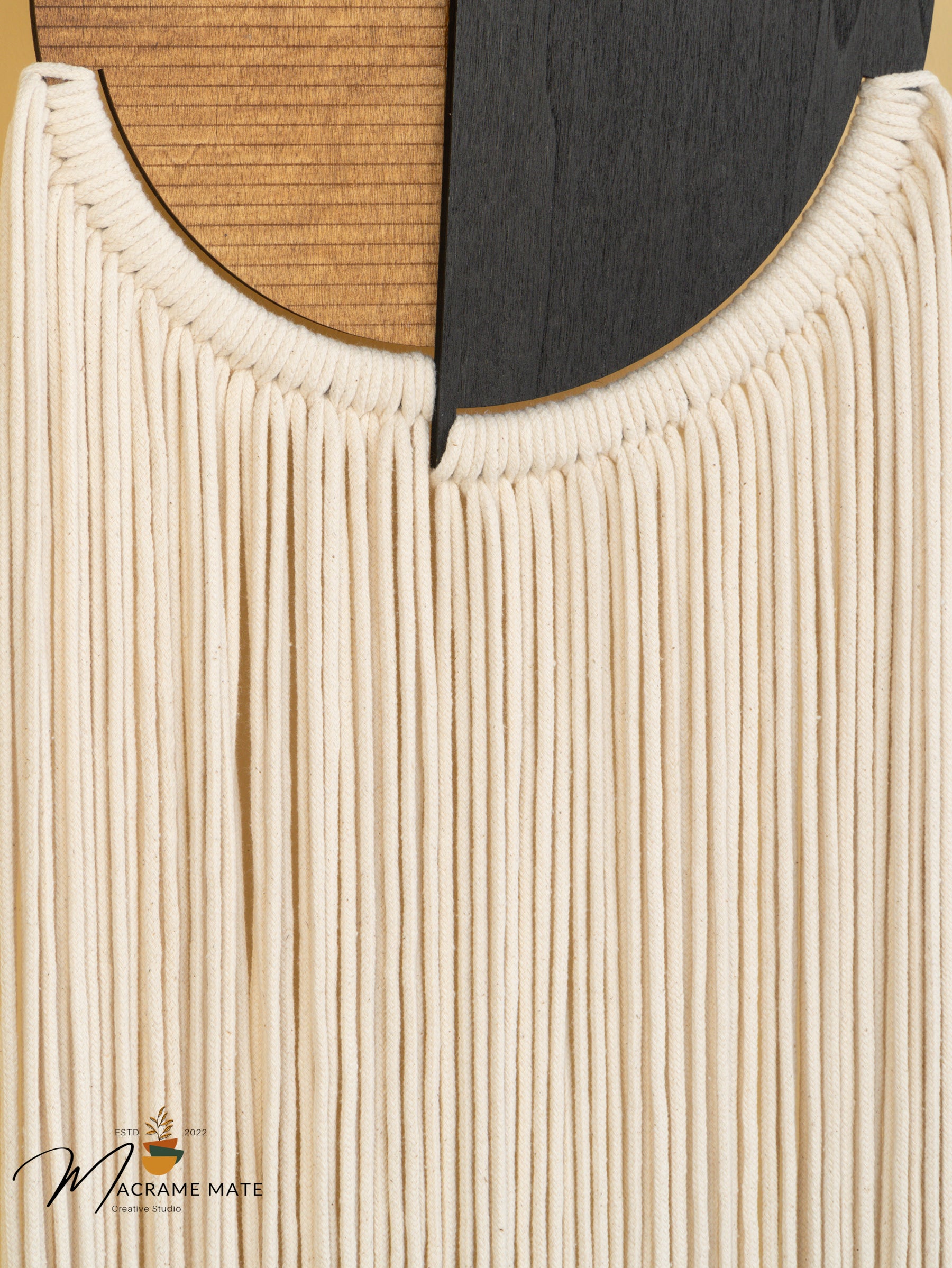 Close-up of a woven wall art piece with natural and black colors.