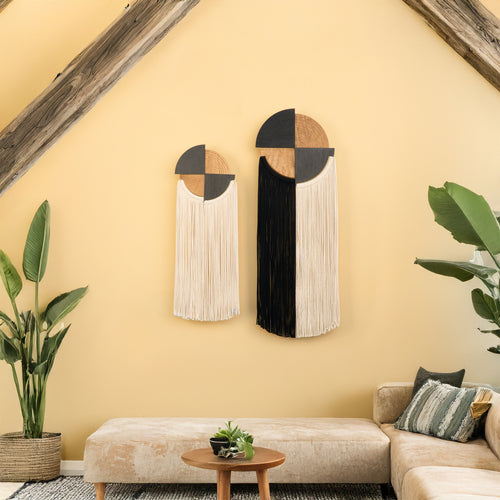 Decorative wall art pieces on a yellow wall with a beige sofa and plants.