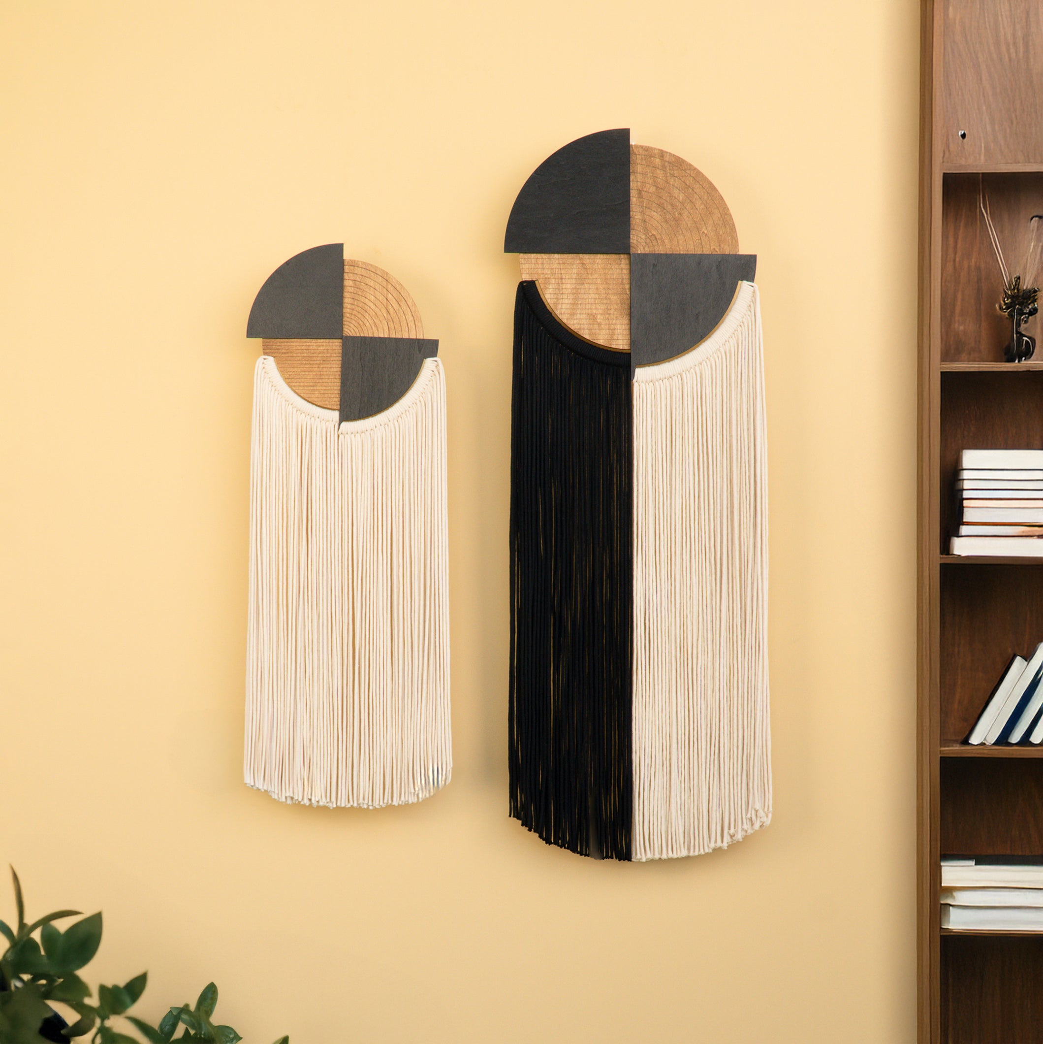 Decorative wall art pieces with geometric design on a yellow wall next to a bookshelf.