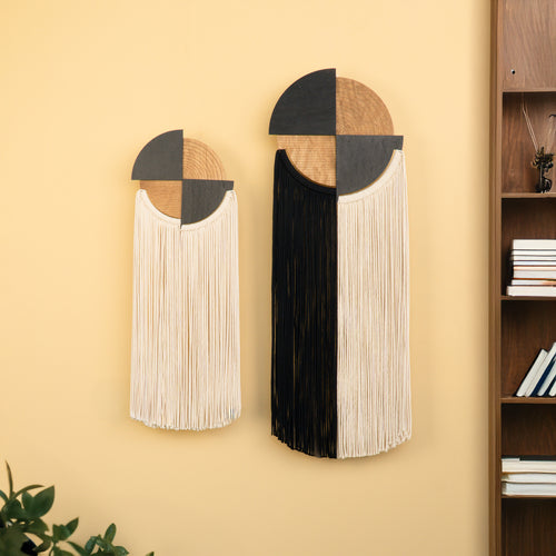 Decorative wall art pieces with geometric design on a yellow wall next to a bookshelf.