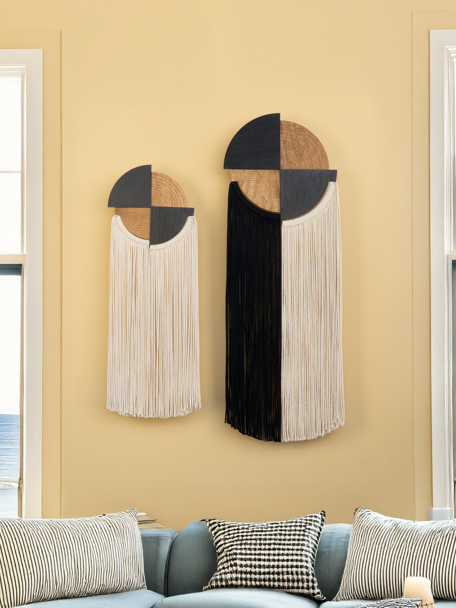 Decorative wall hangings with geometric design on a beige wall.
