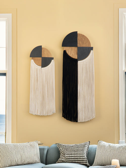 Decorative wall hangings with geometric design on a beige wall.