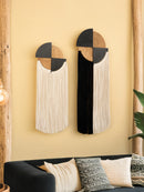 Two abstract wall hangings with geometric design on a yellow wall.