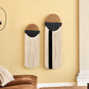 Two decorative wall hangings on a yellow wall with a brown sofa and white rug.