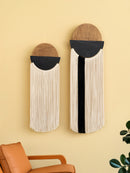 Two wall-mounted decorative items with woven top sections and fringe below on a yellow wall.