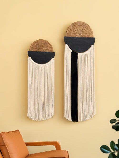 Two wall-mounted decorative items with woven top sections and fringe below on a yellow wall.