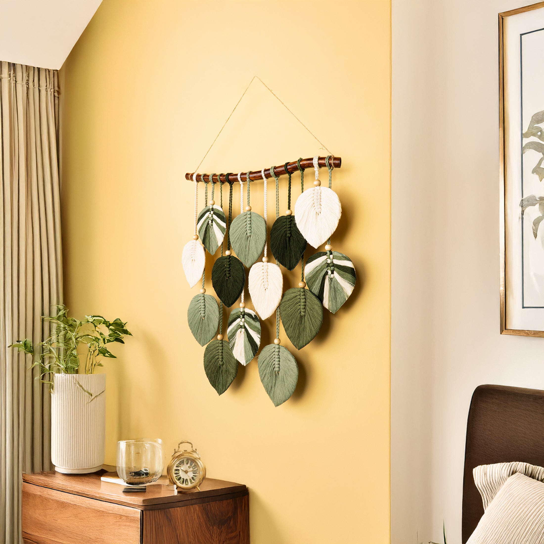 Decorative wall hanging with leaf patterns on a yellow wall in a room.