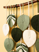 Decorative leaf-shaped ornaments hanging from a rod against a yellow background