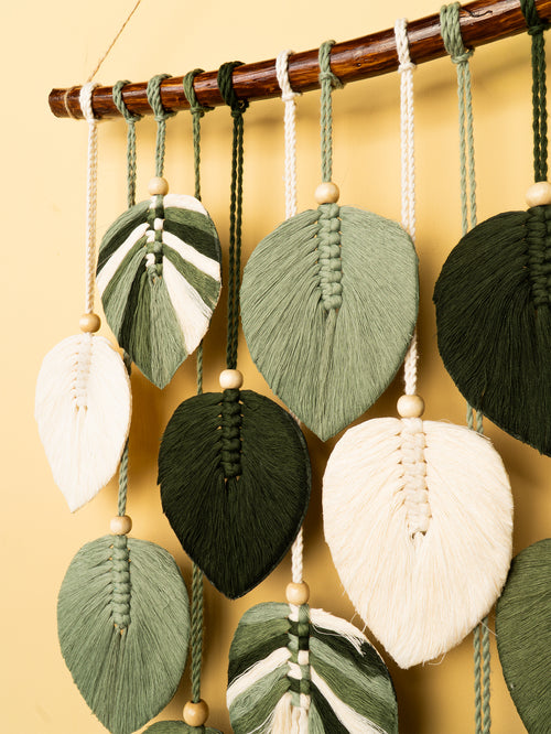 Decorative leaf-shaped ornaments hanging from a rod against a yellow background