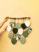 Decorative wall hanging with leaf-shaped ceramic pieces on a yellow background