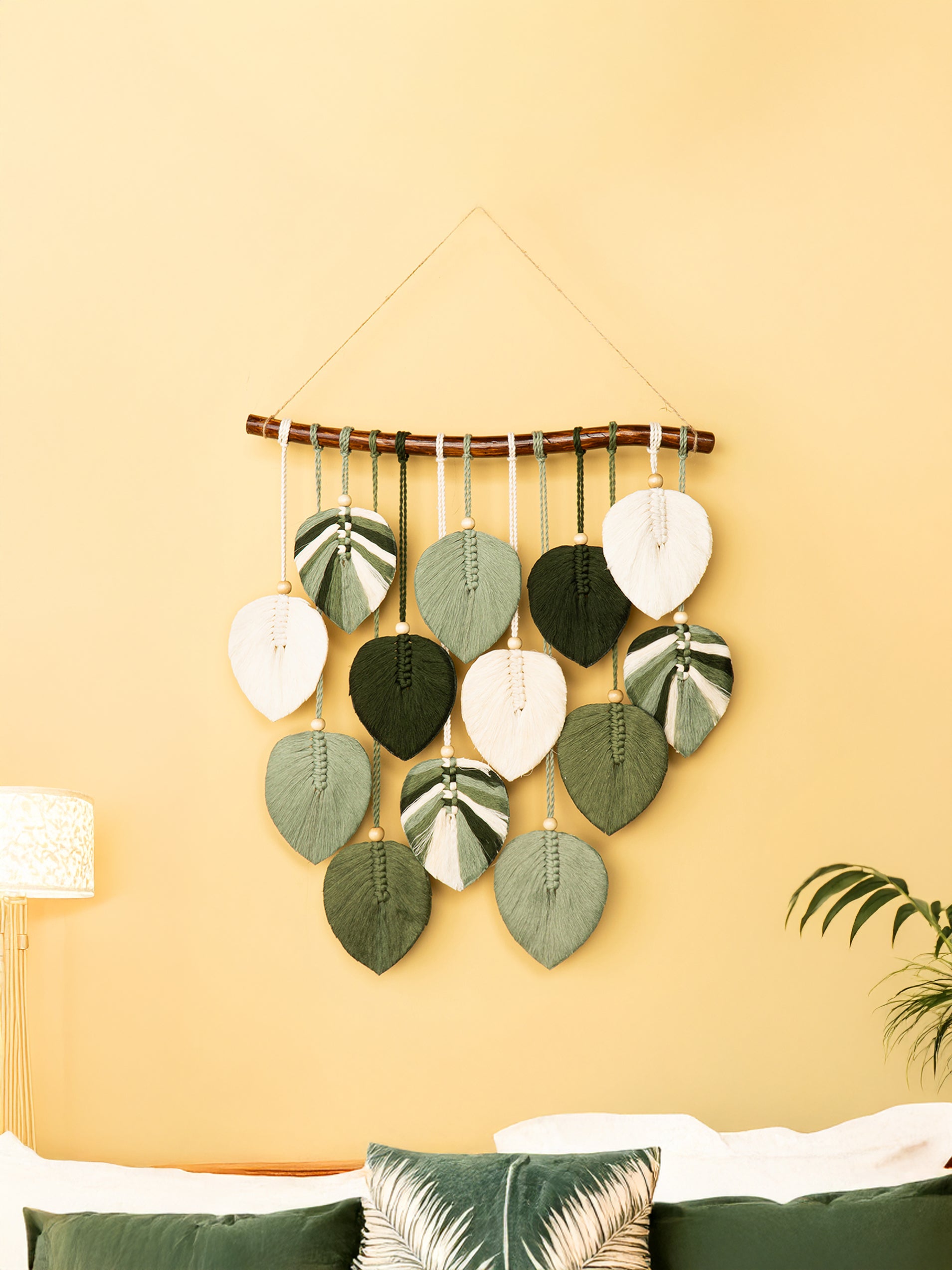 Decorative wall hanging with leaf-shaped elements on a yellow wall.