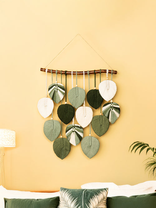 Decorative wall hanging with leaf-shaped elements on a yellow wall.