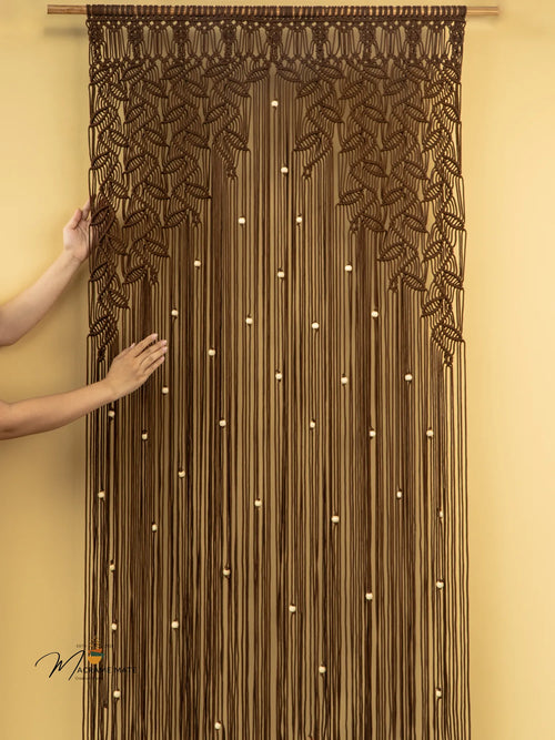 Brown beaded curtain with leaf patterns on a beige wall