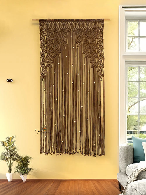 Decorative string curtain hanging on a yellow wall with a window and plant in the background.