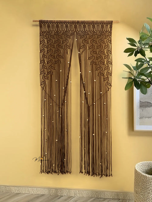Brown beaded curtain hanging on a yellow wall with a plant and decorative item in the corner.