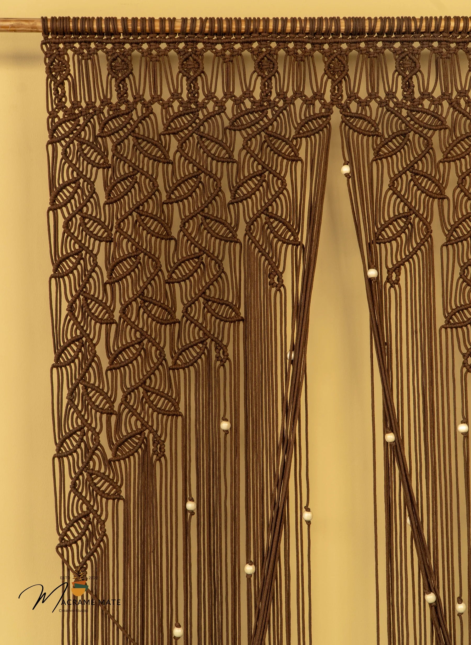 Decorative macrame curtain with leaf patterns on a beige background
