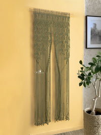 Decorative string curtain hanging on a yellow wall with a plant and framed picture in the background.