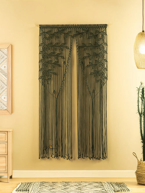 Textured wall art hanging on a beige wall with a light fixture and plant in the background.