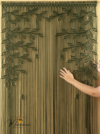 Decorative curtain with leaf pattern held by a hand, brand visible