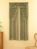 Decorative string curtain hanging on a beige wall with a wicker chair and plant in the foreground.