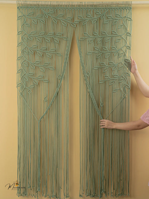 Green macramé curtain being held against a yellow wall